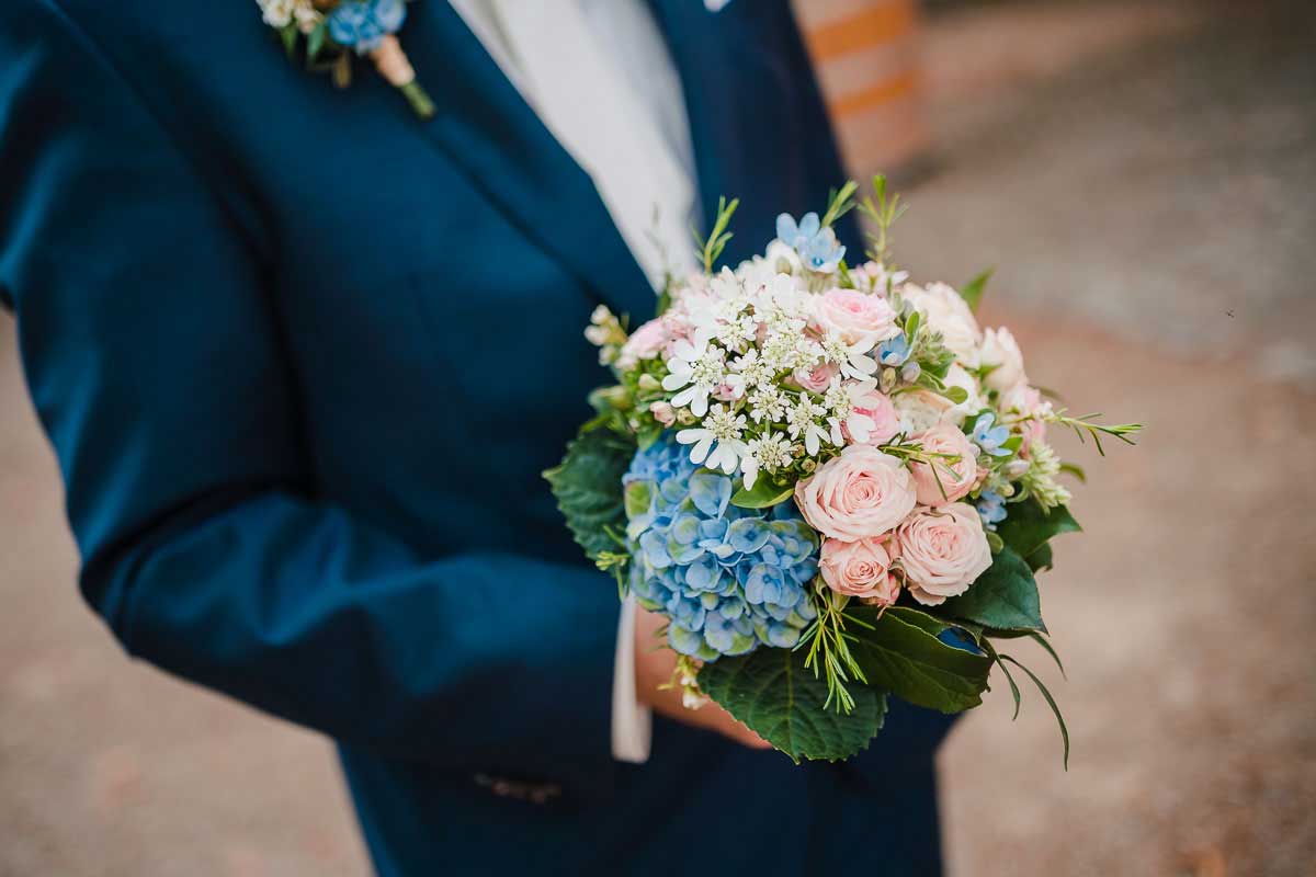 Bräutigam wartet mit Blumenstrauss der Braut