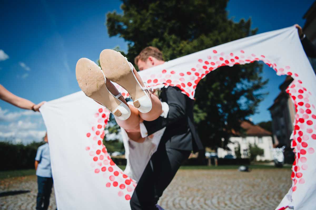 Bräutigam trägt Braut durch ein ausgeschnittenes Herz